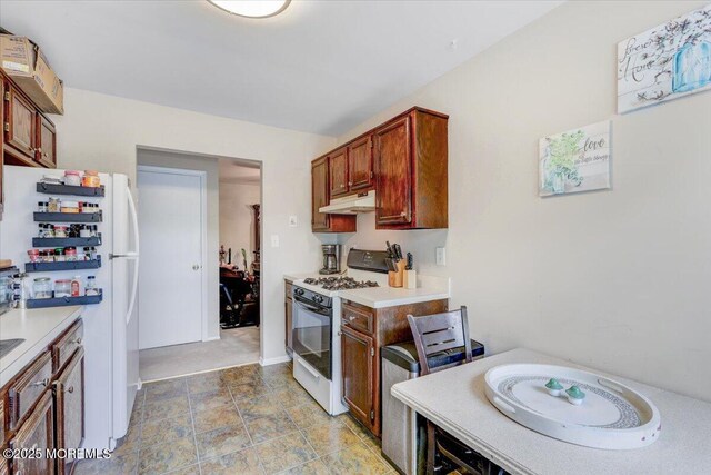 82 Briarwood Ct, Howell, NJ 07731 - kitchen featuring range with gas cooktop, under cabinet range hood, freestanding refrigerator, light countertops, and baseboards