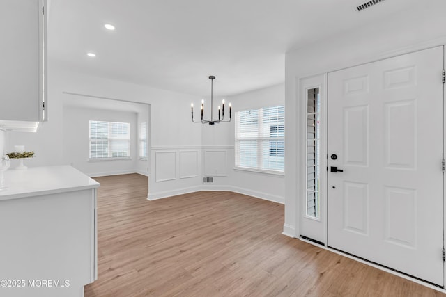 foyer with a chandelier, healthy amount of natural light, light wood-style flooring, and recessed lighting