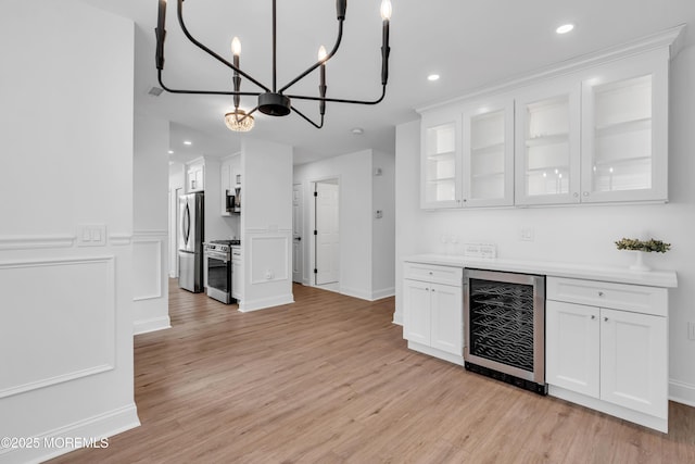 indoor dry bar with wine cooler, stainless steel appliances, light wood-type flooring, recessed lighting, and a chandelier