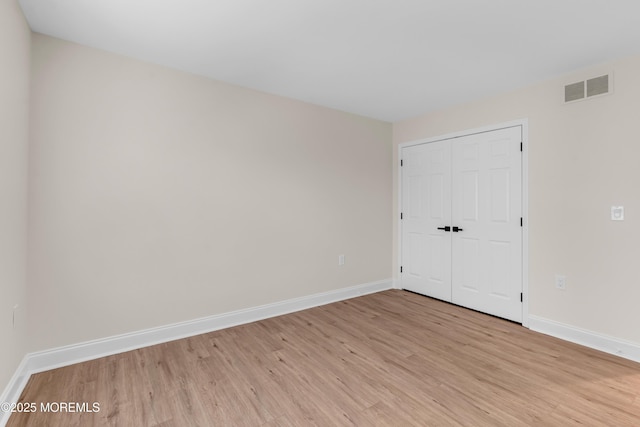 unfurnished bedroom featuring light wood-style flooring, baseboards, and a closet