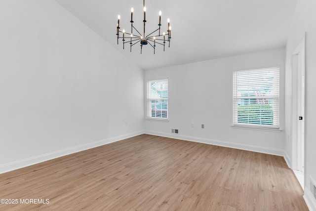 empty room featuring a chandelier, light wood-style flooring, baseboards, and lofted ceiling
