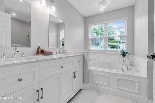 bathroom featuring marble finish flooring, a garden tub, and double vanity