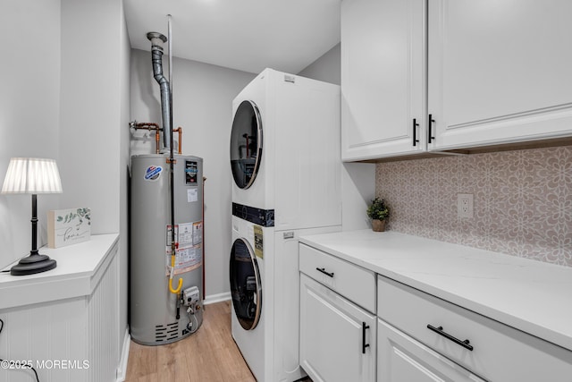 clothes washing area with gas water heater, estacked washer and dryer, light wood finished floors, and cabinet space