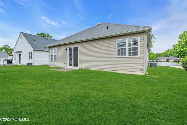 rear view of house featuring central AC, a yard, and a shingled roof