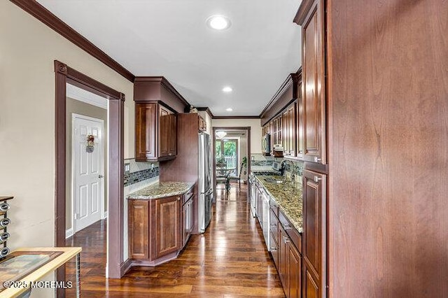 kitchen with appliances with stainless steel finishes, dark stone countertops, ornamental molding, dark wood-style floors, and decorative backsplash