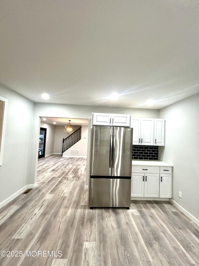 kitchen with freestanding refrigerator, light wood-style flooring, white cabinetry, and baseboards