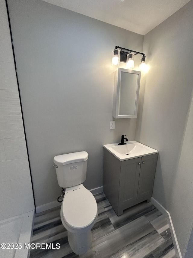 bathroom featuring wood finished floors, toilet, vanity, and baseboards