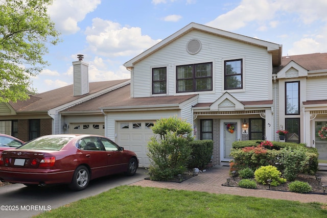 view of front facade featuring concrete driveway, a chimney, and an attached garage