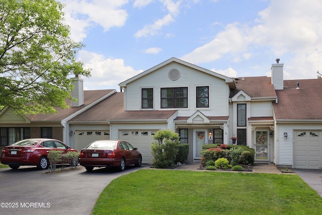 view of front of home featuring driveway, a chimney, a front lawn, and a garage