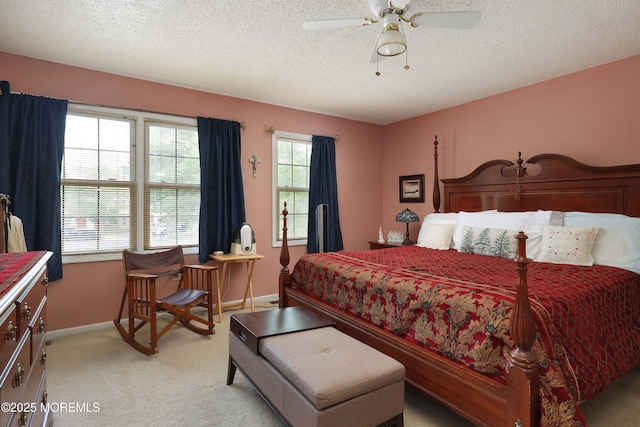 bedroom with light colored carpet, baseboards, a textured ceiling, and ceiling fan
