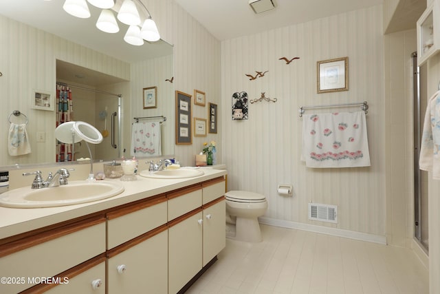 bathroom with tile patterned floors, wallpapered walls, a stall shower, toilet, and double vanity