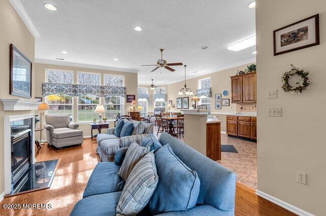 living room featuring crown molding, a ceiling fan, recessed lighting, a premium fireplace, and light wood-style flooring