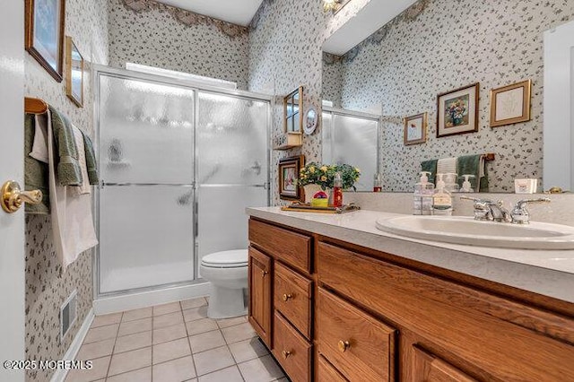 full bathroom with wallpapered walls, tile patterned flooring, a stall shower, toilet, and double vanity