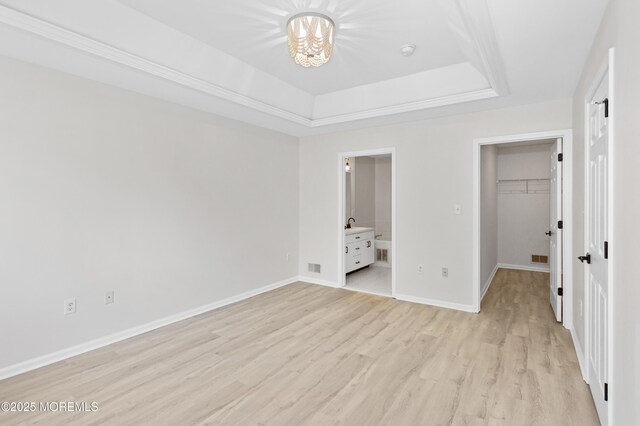 52 Straton Ct Unit 1006, Parlin, NJ 08859 - unfurnished bedroom with a tray ceiling, light wood-style flooring, a walk in closet, a chandelier, and baseboards