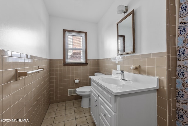 full bathroom with tile patterned flooring, wainscoting, toilet, tile walls, and vanity