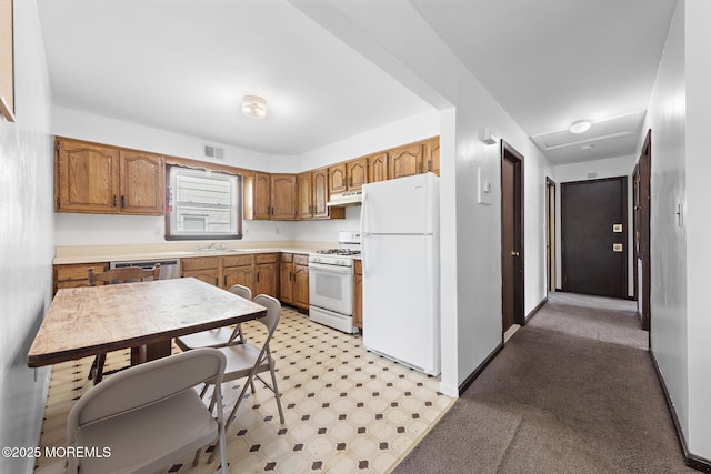 kitchen with white appliances, a sink, brown cabinets, light countertops, and under cabinet range hood