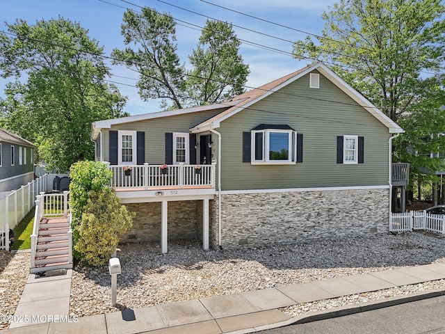 view of front of property with stone siding, fence, and stairway