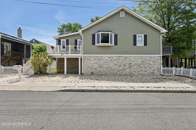 view of front of home featuring stone siding, fence, and stairway