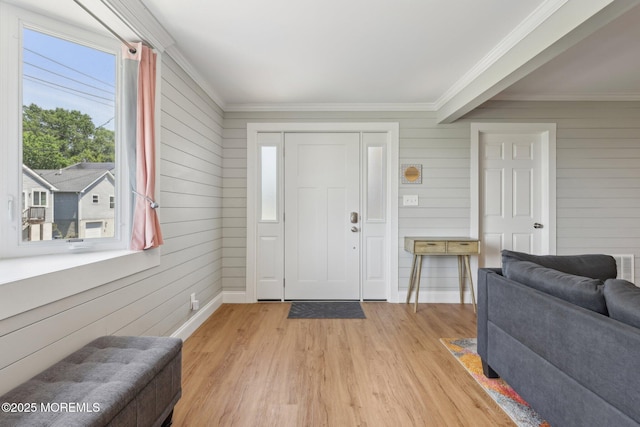entryway with crown molding, light wood-style floors, wood walls, and baseboards