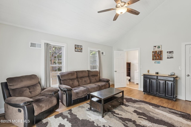 living area featuring a ceiling fan, light wood-style flooring, high vaulted ceiling, and baseboards
