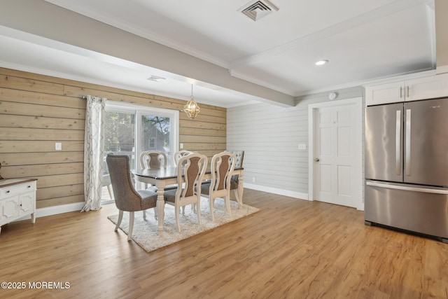 dining room with crown molding, baseboards, light wood-type flooring, wooden walls, and recessed lighting