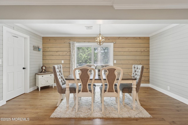 dining area with ornamental molding, wood finished floors, baseboards, and wood walls