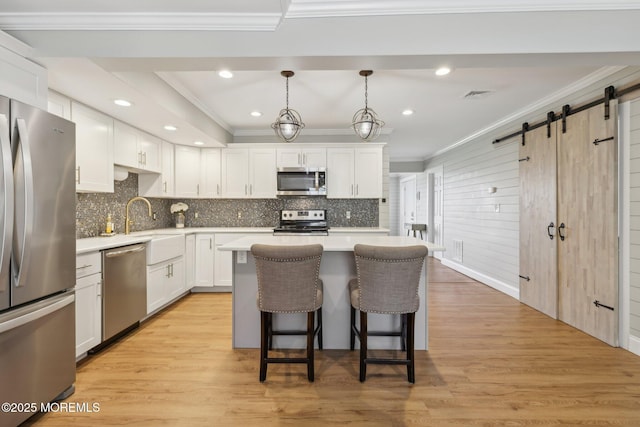 kitchen with stainless steel appliances, crown molding, a kitchen bar, a center island, and decorative backsplash