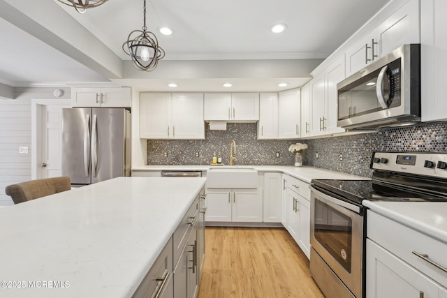 kitchen featuring appliances with stainless steel finishes, ornamental molding, a sink, light countertops, and backsplash