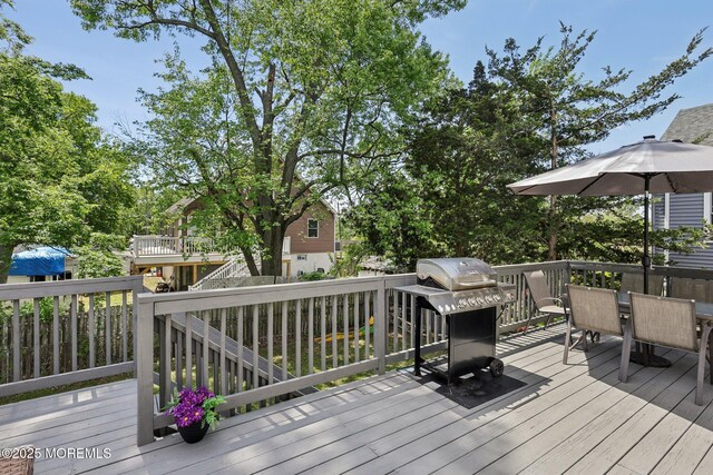 wooden deck with outdoor dining area and grilling area
