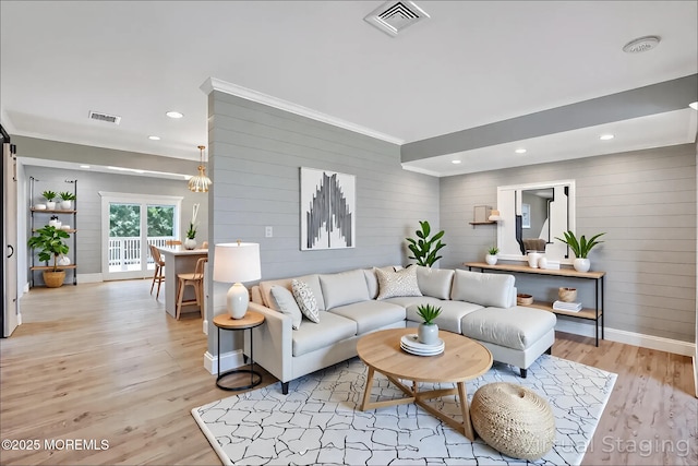 living room featuring wooden walls, baseboards, light wood-style flooring, ornamental molding, and recessed lighting