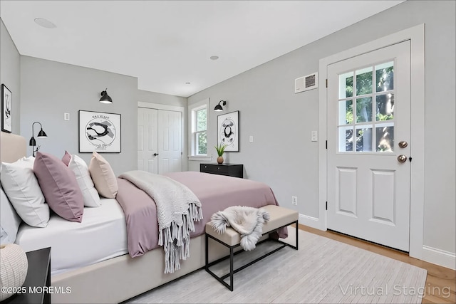 bedroom featuring multiple windows, light wood-type flooring, a closet, and baseboards