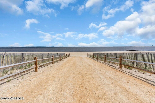 view of dirt / gravel road featuring view of water and beach