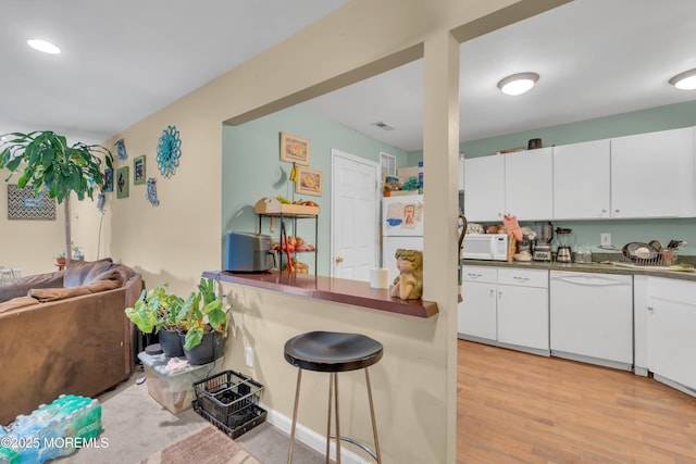 707 Zlotkin Cir Unit 7, Freehold, NJ 07728 - kitchen featuring white appliances, dark countertops, light wood finished floors, white cabinets, and a kitchen breakfast bar