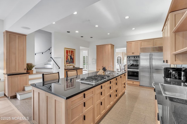 kitchen featuring appliances with stainless steel finishes, light brown cabinets, a sink, recessed lighting, and a spacious island
