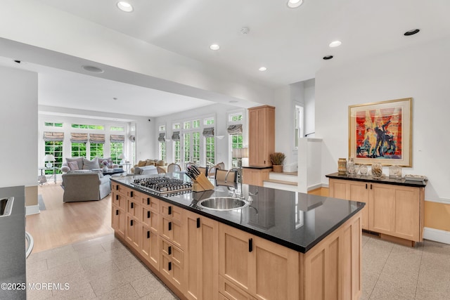 kitchen featuring a sink, light brown cabinets, stainless steel gas cooktop, open floor plan, and baseboards