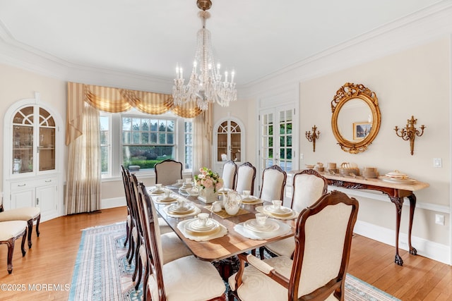 dining room with a chandelier, light wood-style flooring, crown molding, and baseboards
