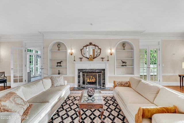 living area featuring built in features, french doors, a premium fireplace, crown molding, and plenty of natural light