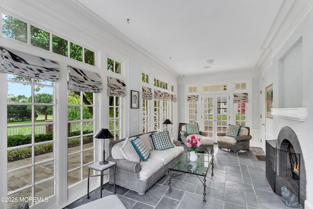 sunroom / solarium featuring french doors, crown molding, and stone tile floors