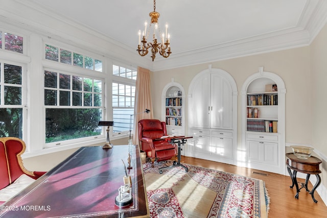 office area featuring crown molding, a chandelier, wood finished floors, and built in shelves