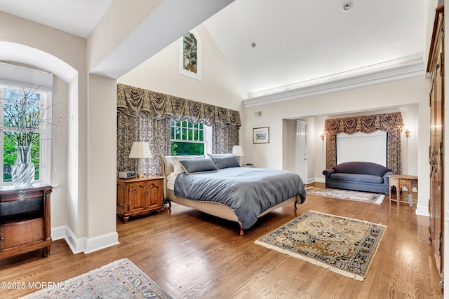 bedroom with high vaulted ceiling, baseboards, and wood finished floors