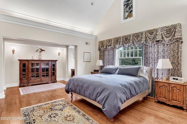bedroom with light wood-type flooring and high vaulted ceiling