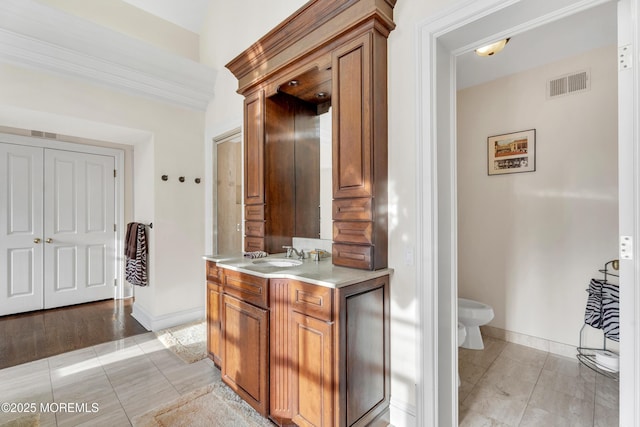 kitchen featuring light countertops, a sink, brown cabinetry, light tile patterned flooring, and baseboards