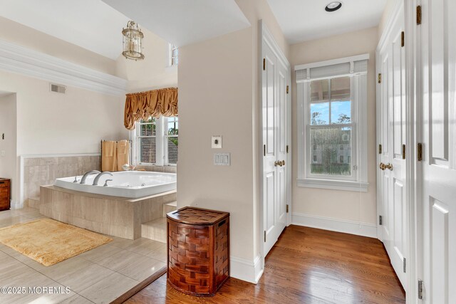bathroom with a bath, baseboards, and wood finished floors