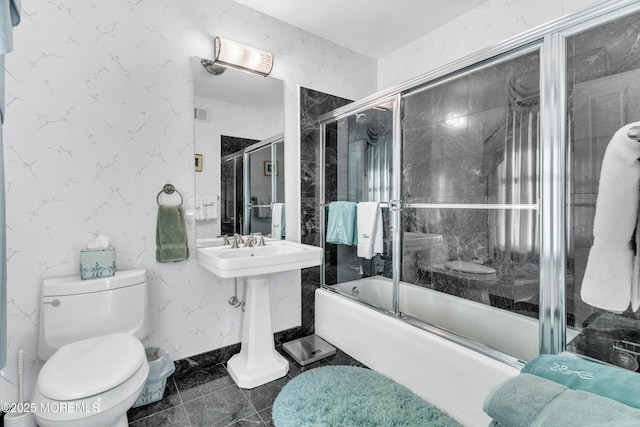 full bathroom with toilet and bath / shower combo with glass door
