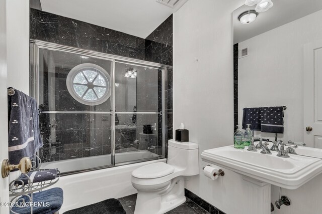 full bath featuring toilet and bath / shower combo with glass door