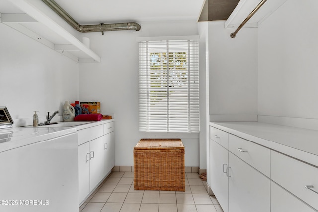 clothes washing area featuring washer / clothes dryer, light tile patterned floors, cabinet space, and baseboards