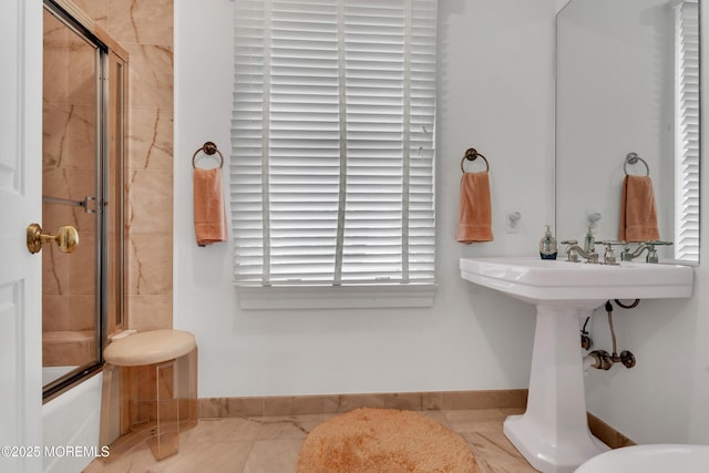 full bath featuring baseboards and shower / bath combination with glass door
