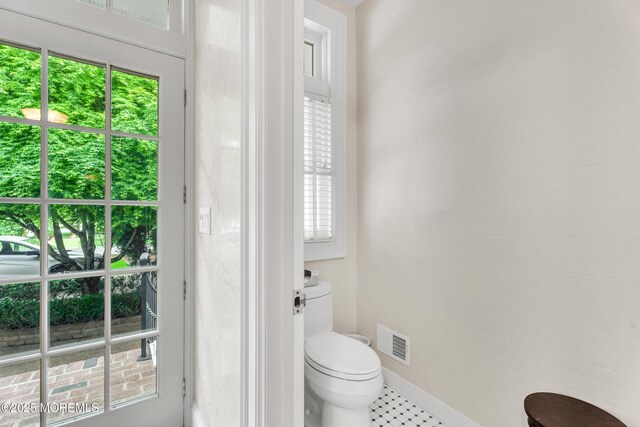 bathroom featuring healthy amount of natural light, toilet, and baseboards
