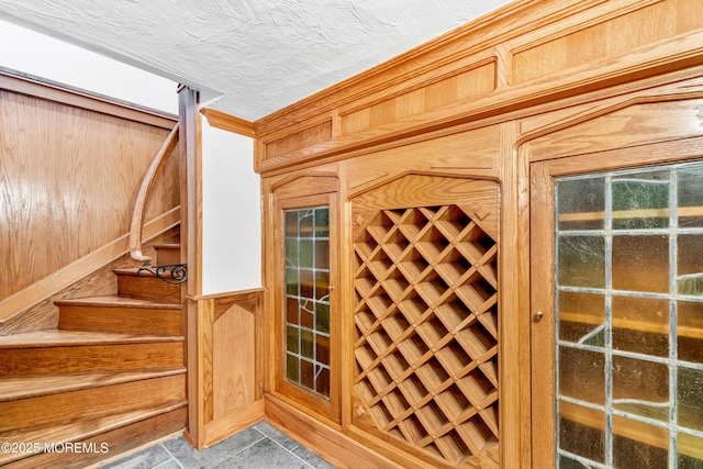 wine area featuring wood walls, tile patterned floors, and a textured ceiling