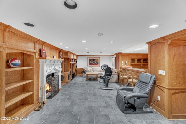 living room featuring recessed lighting, a lit fireplace, and built in shelves